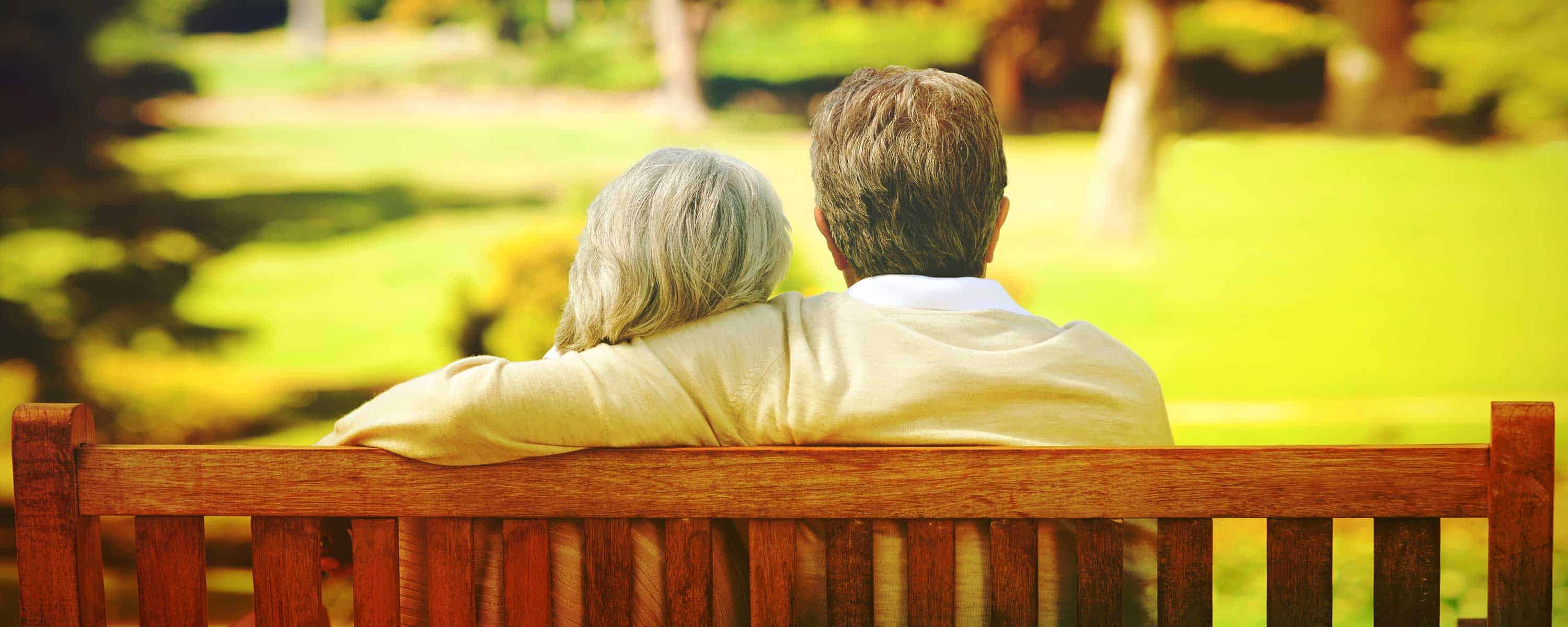 An older couple sitting on a park bench.